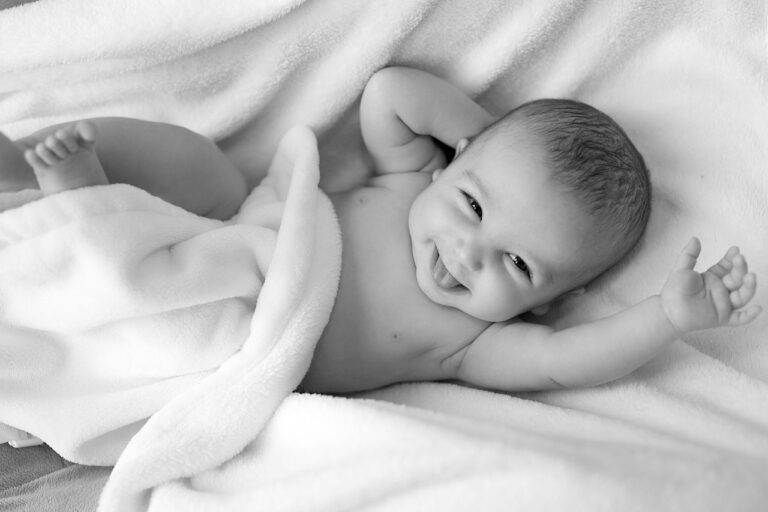 Foto de bebé sonriendo en la cama en blanco y negro.