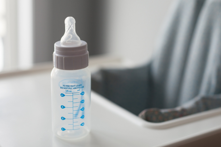 Biberón de plástico sobre una trona.