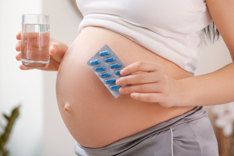 Embarazada con pastillas de ácido fólico en la mano