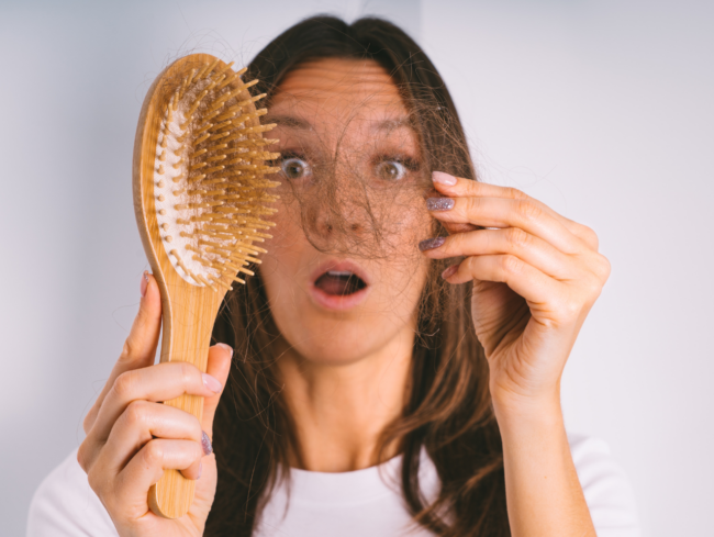 Mujer sujetando un cepillo lleno de pelo