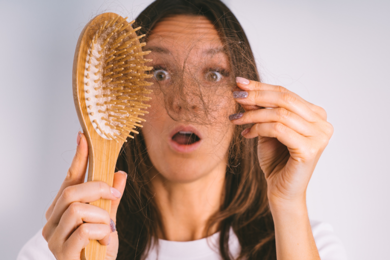 Mujer sujetando un cepillo lleno de pelo