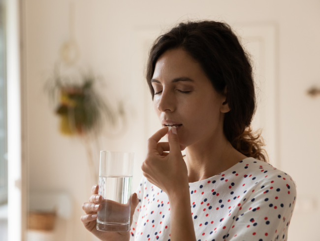 Mujer de mediana edad tomando un antidepresivo con un vaso de agua